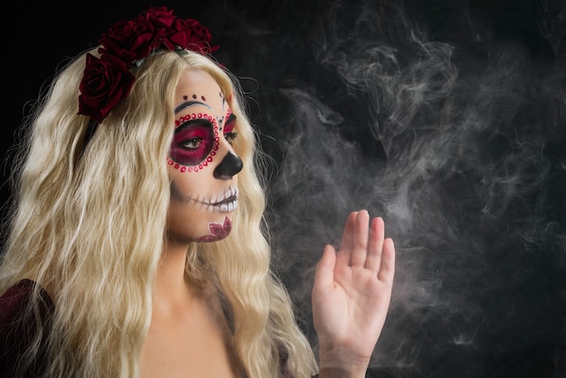 Woman with sugar skull makeup and blond hair isolated on black background. Day of the dead. Halloween.  Copy space.