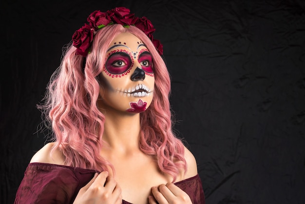 Woman with sugar skull makeup and pink hair isolated on black background. Day of the dead. Halloween.  Copy space.