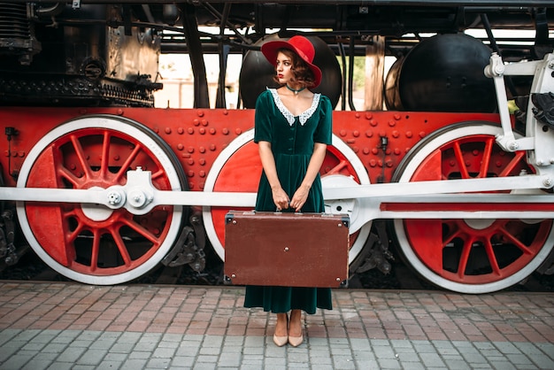 Woman with suitcase against steam locomotive