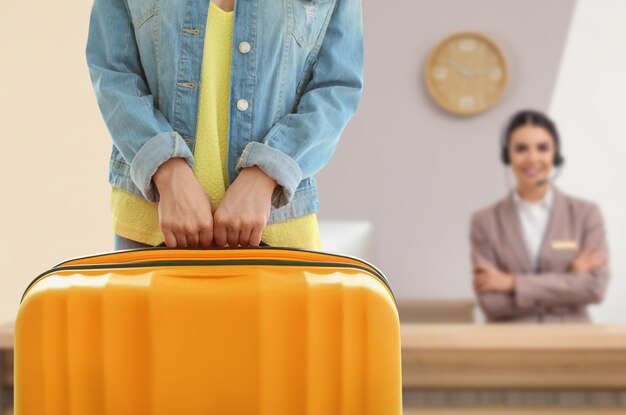 Woman with suitcase near receptionist in hotel closeup view