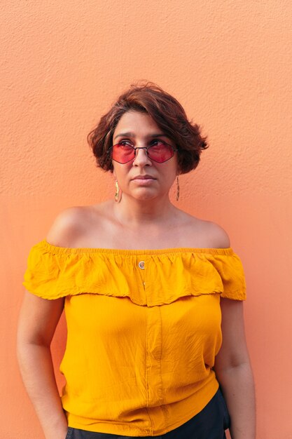 Woman with sunglasses on orange background.