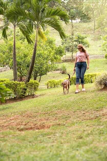 公園で犬と歩いているサングラスをかぶった女性