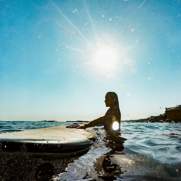 Donna con tavola da surf in acqua