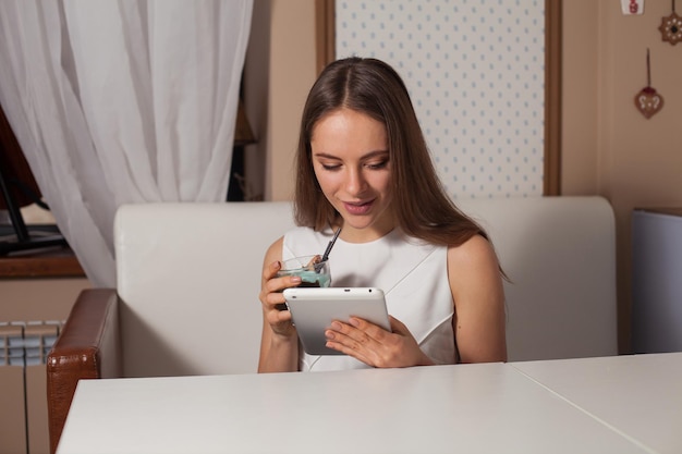 カフェでタブレットと飲み物を持つ女性