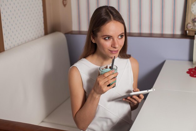 カフェでタブレットと飲み物を持つ女性