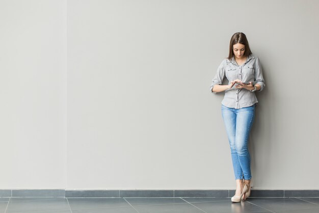 壁のそばのタブレットを持つ女性