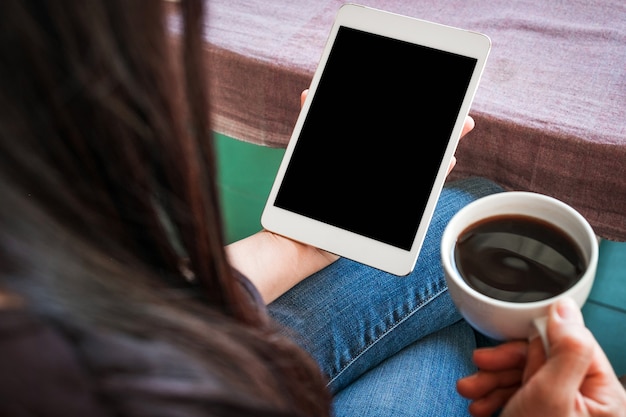 Woman with tablet and cup of coffee in hands