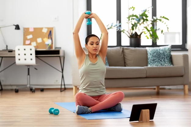 woman with tablet pc and dumbbell training at home