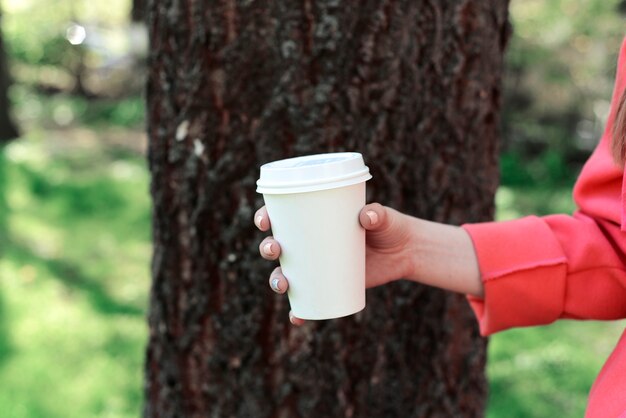 公園でテイクアウトのコーヒーを持つ女性