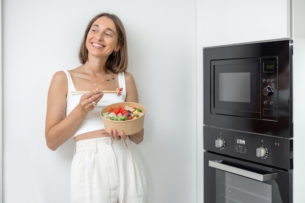 自宅のモダンなキッチンで持ち帰り用の食べ物を持つ女性