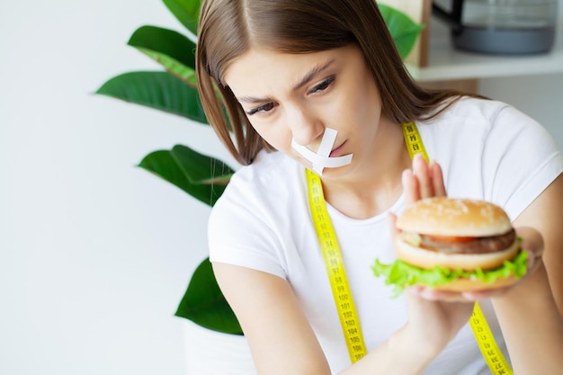 Woman with a taped mouth sits at a table with fast food