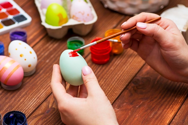 イースター用の装飾を準備するイースターの卵を描くタッセルを持った女性