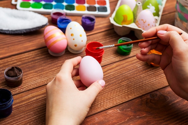 A woman with a tassel paints Easter eggs