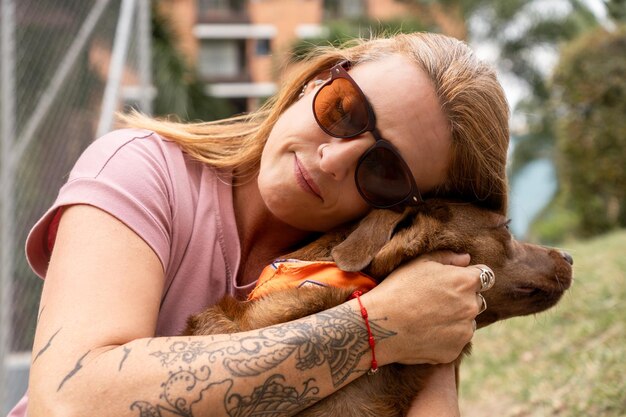 A woman with a tattooed arm lovingly embraces her pet