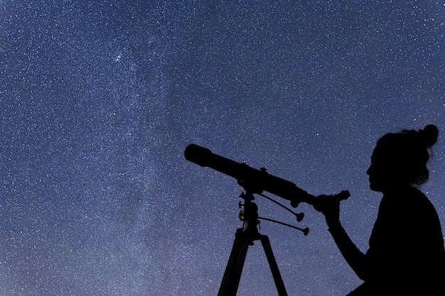 星を見ている望遠鏡を持つ女性。星空の女性