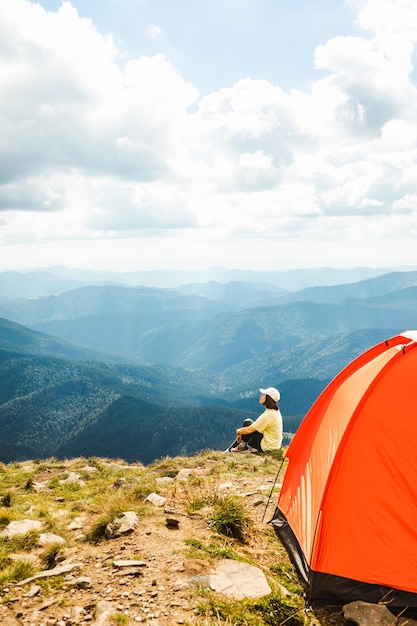 Woman with a tent on top of a mountain