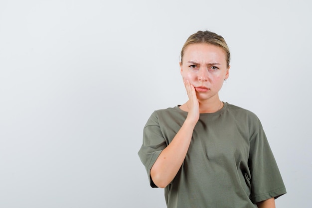 The woman with toothache is putting hand on cheek on white background