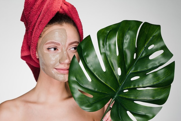 Woman with towel on her head after shower apply cleansing mask on face