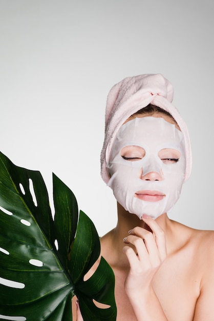 Photo a woman with a towel on her head after showering the mask with a film on her face