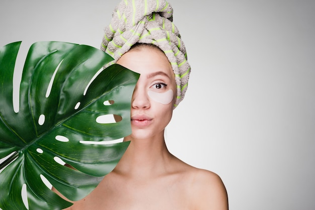 A woman with a towel on her head after showering patches under her eyes