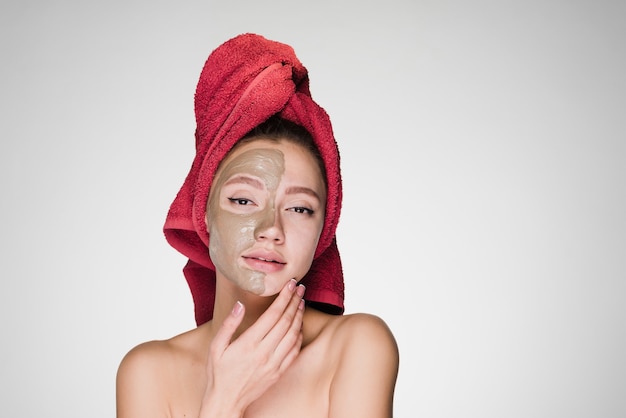 Woman with a towel on her head apply a cleansing mask on her face