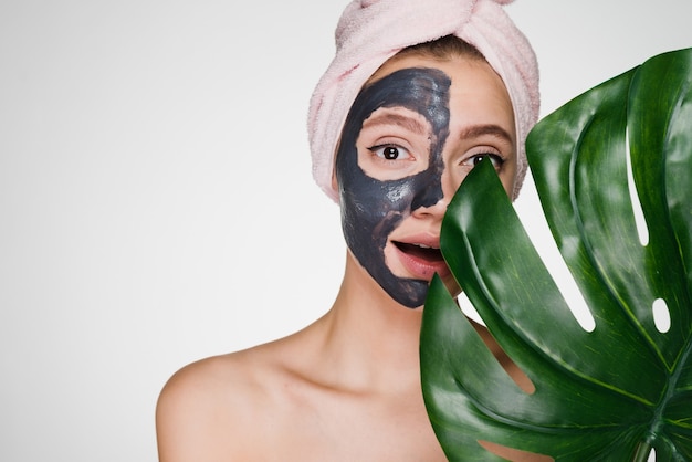 Photo a woman with a towel on her head apply a cleansing mask on problem areas of the skin