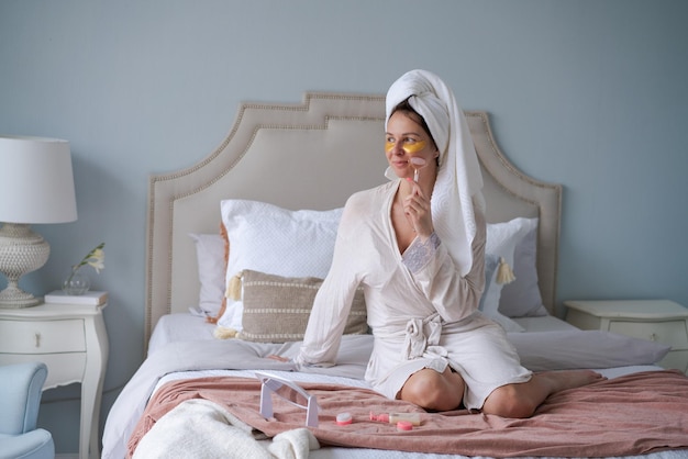 Woman with towel on her head doing beauty routine with gua sha quartz roller