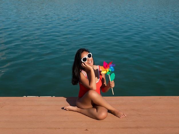 Woman with toy windmill on pier near sea