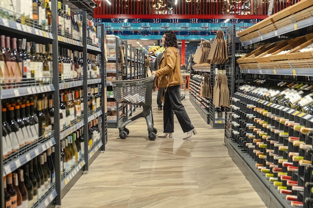 A woman with a trolley makes purchases in a supermarket