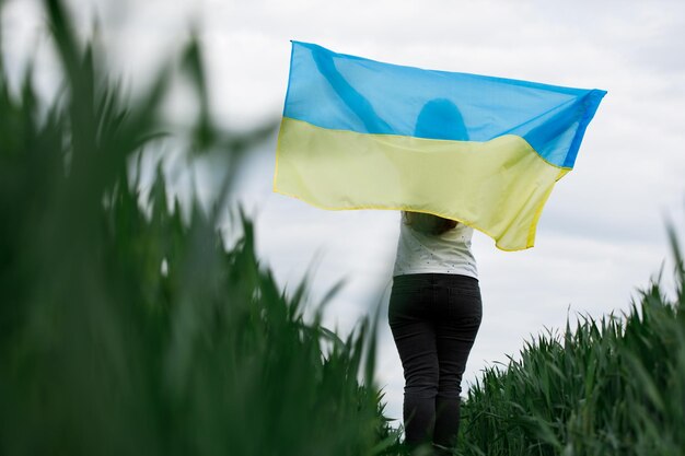 Woman with Ukrainian flag in wheat fieldHappy woman celebrating Independence Day