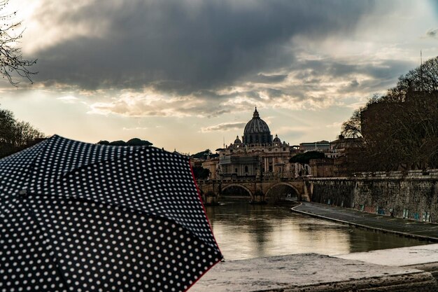 Photo woman with umbrella in front of the san pietro in vaticano in a cloudy sky