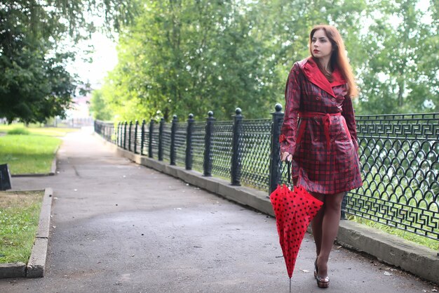 Donna con ombrello rosso su albero di strada