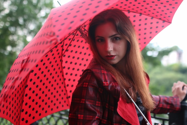 Woman with umbrella red on street tree