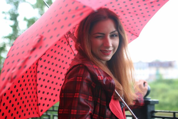 Woman with umbrella red on street tree