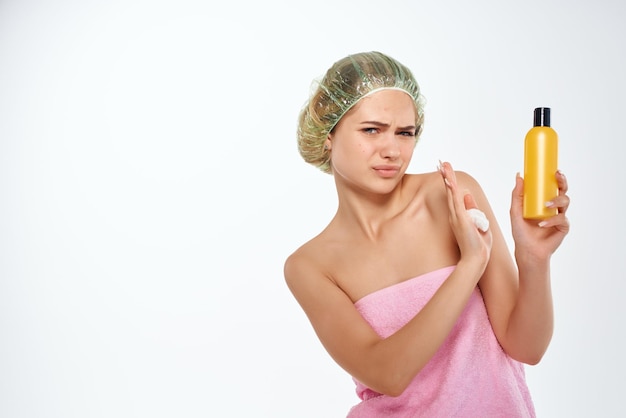 Woman with unhappy facial expression in pink towel lotion skin care