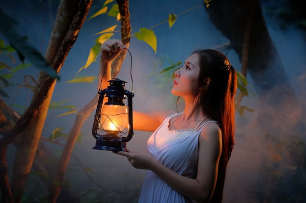 woman with vintage lantern outside at night