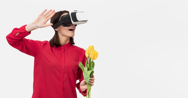 Donna con la cuffia avricolare di realtà virtuale che tiene i fiori