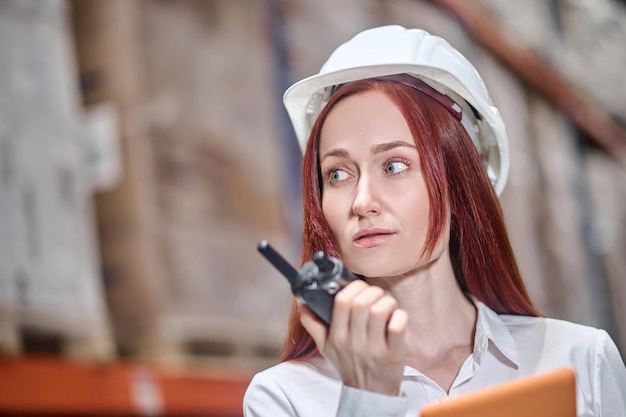 Woman with walkie-talkie in hand looking aside