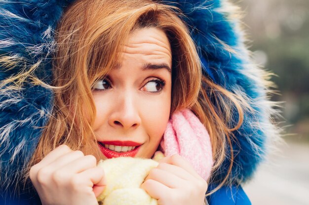 Woman with warm clothes and very cold, looking at the copy
space, with a face of astonishment and surprise at the drop in
temperatures.