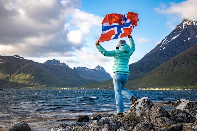 Foto donna con una bandiera sventolante della norvegia sullo sfondo della natura