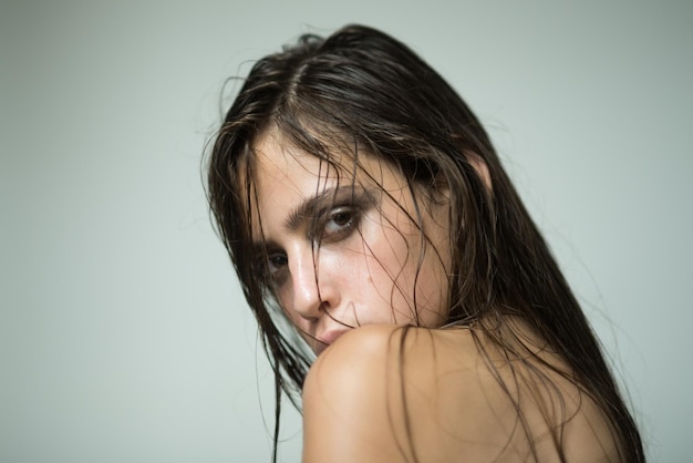 Woman with wet or oily hair on grey background