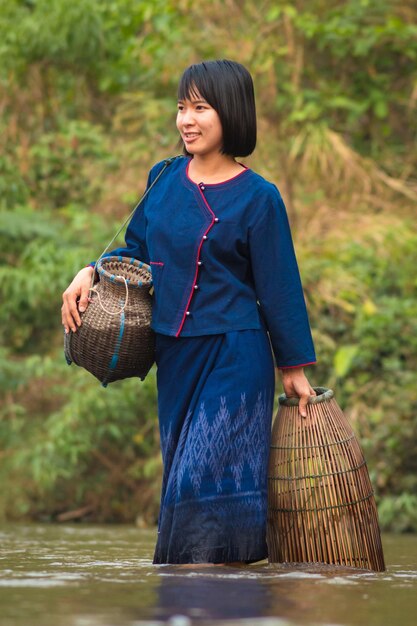 Photo woman with whicker baskets walking in river