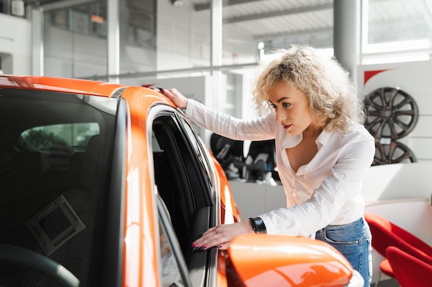 Foto una donna con i capelli ricci bianchi esamina l'interno di un'auto nuova in una concessionaria