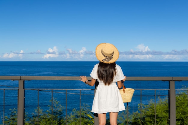 白いドレスを着た女性と青い空の海景色を楽しむ