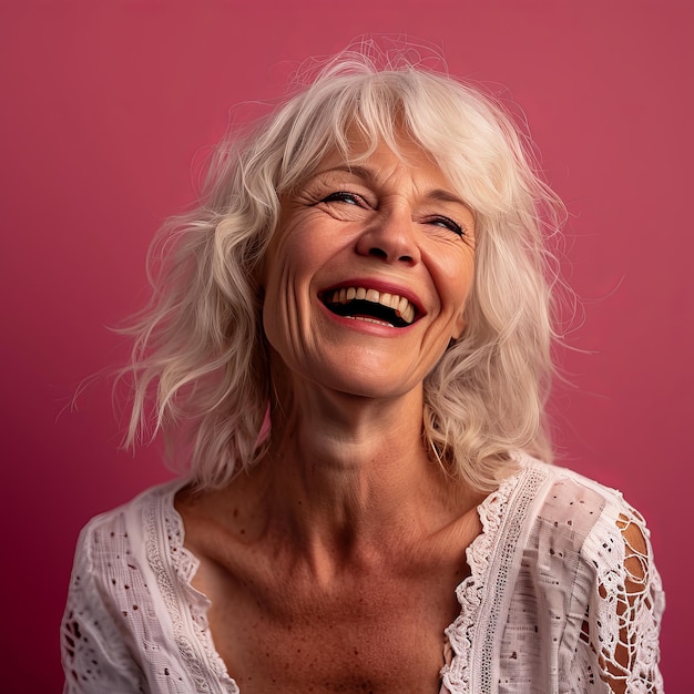 A woman with white hair and a smile on a pink background