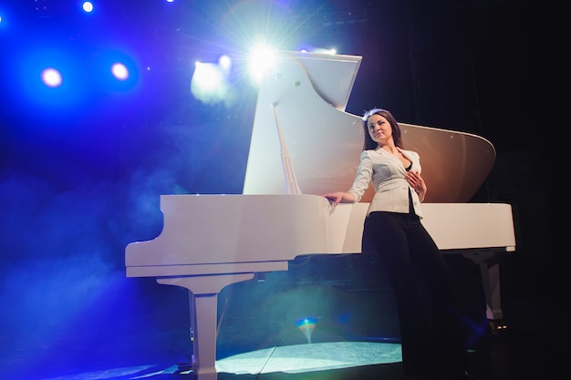 Donna con il pianoforte bianco sul palco.