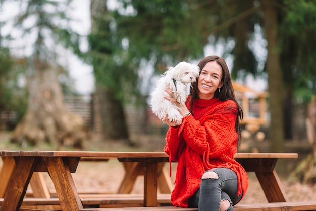 白い子犬を持つ女性。美しい少女の手の中の子犬