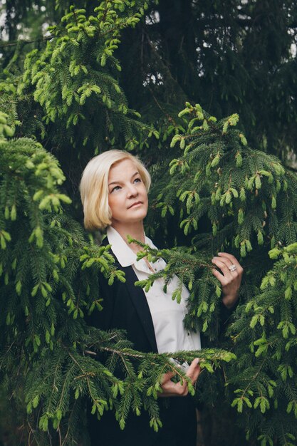 woman with white short hair among the trees.