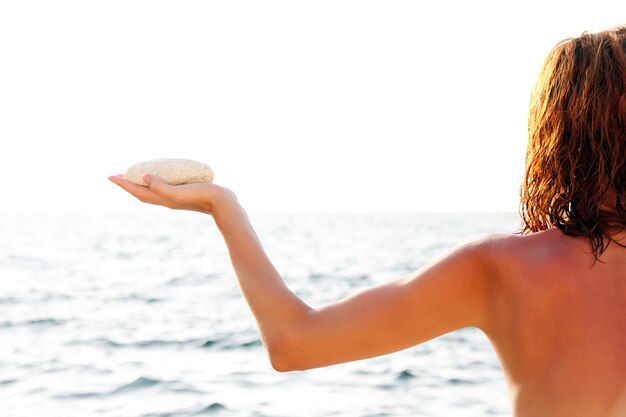 Donna con pietra bianca in riva al mare