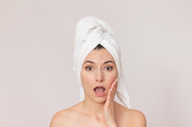 woman with a white towel wrapped around her head who is surprised and putting her hand to her cheek